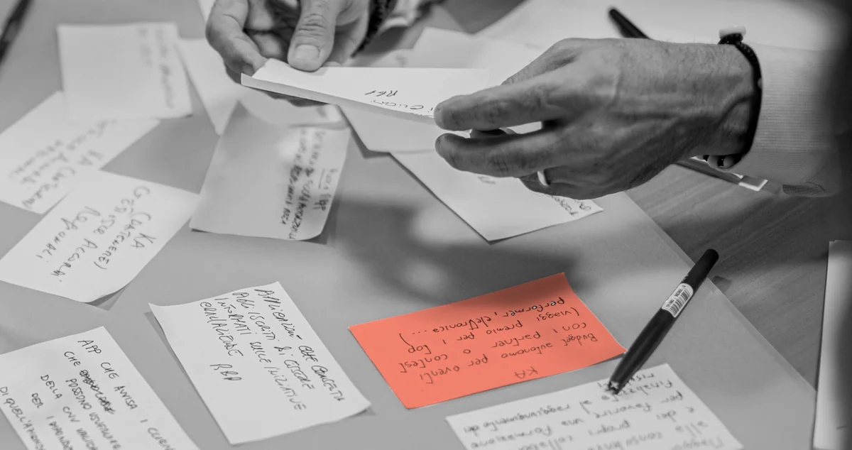 A table covered in written decisions, one held in the hand and picked out in colour